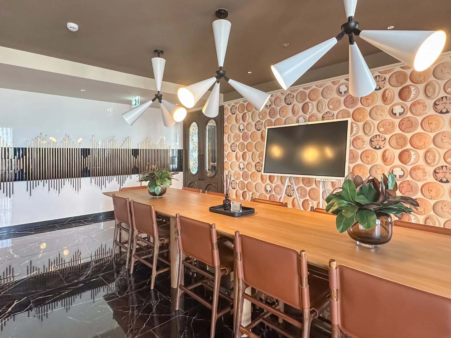 Área común con mostrador de madera, asientos de cuero y pared decorativa de monedas en Noble Form Thonglor, Tailandia
