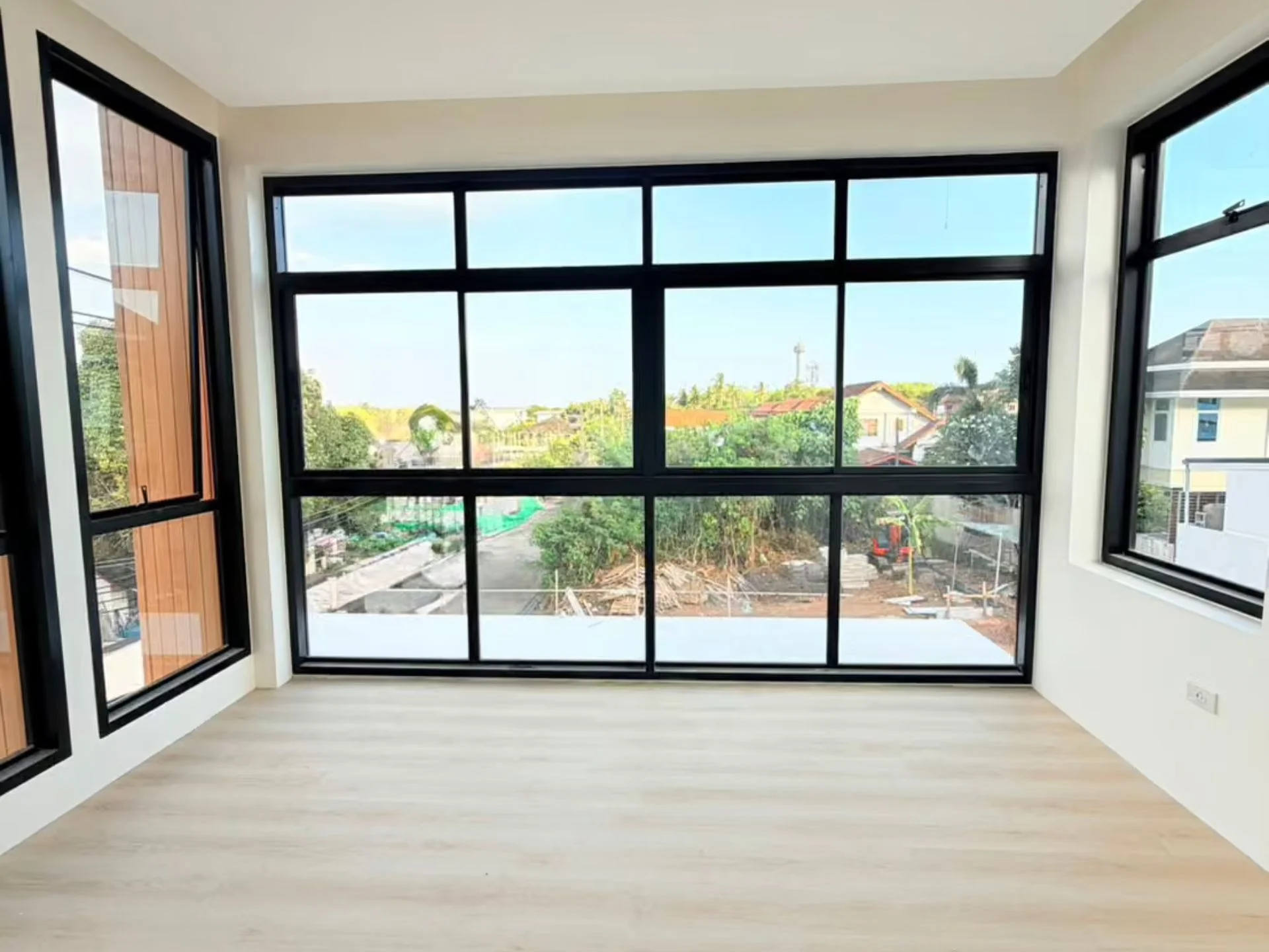 Helles Wohnzimmer mit Panoramafenstern mit Blick auf Wohngebiet in NAI Villas Urban, Chalong