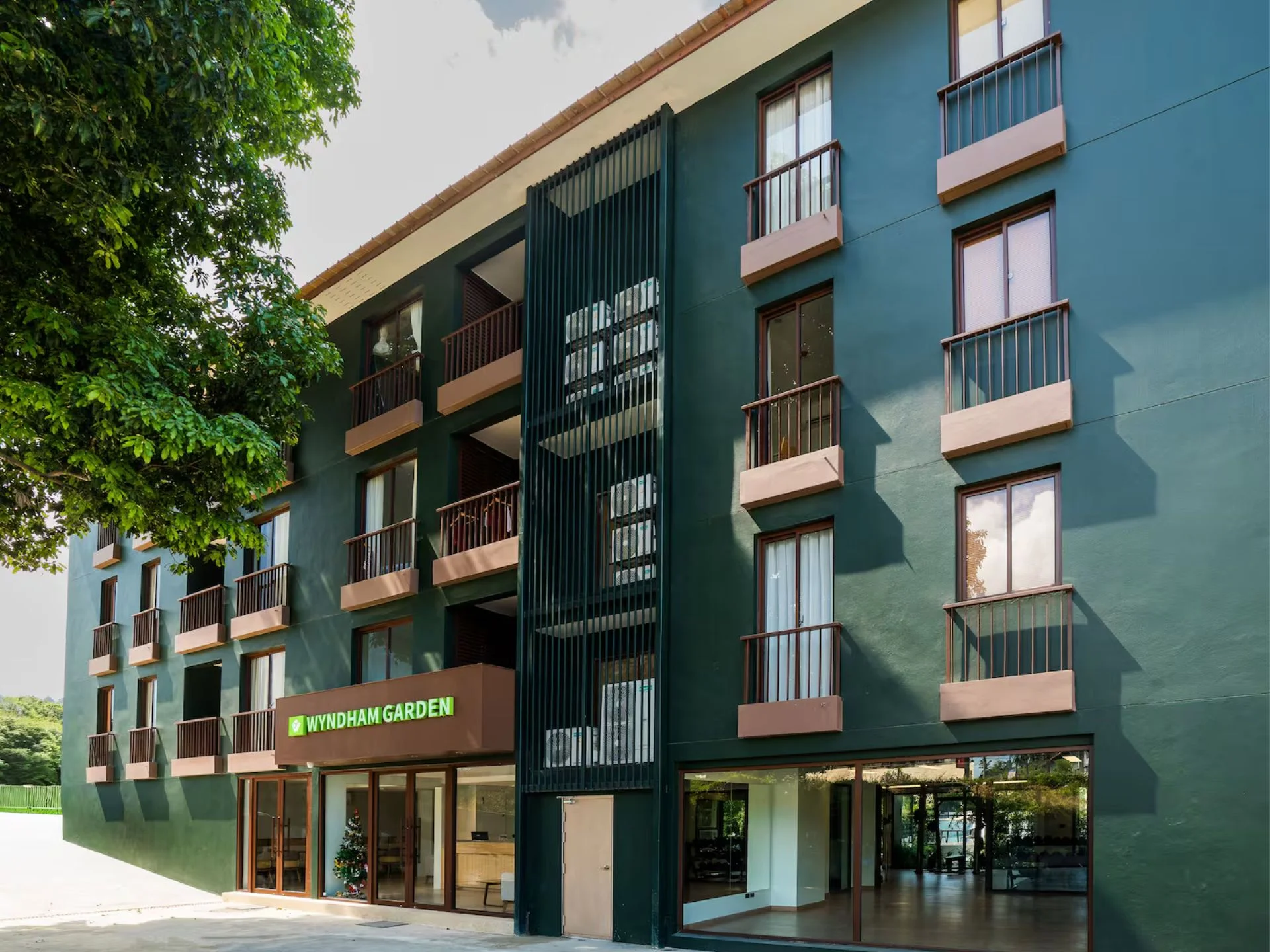 Architecture of Wing Samui residential complex with green facade and ground-level retail, Thailand