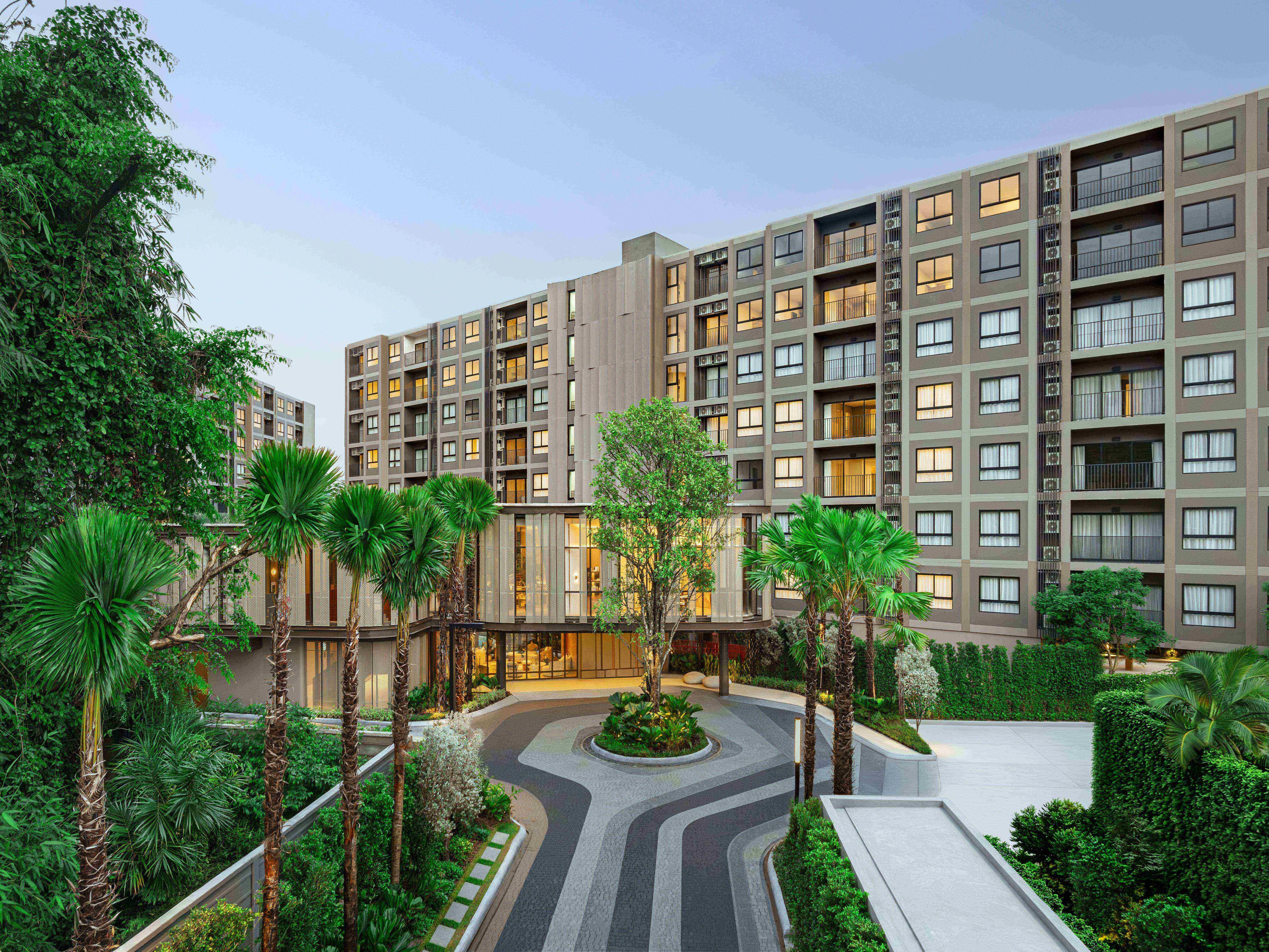Landscaped courtyard with palm trees and modern architecture at The Base Cherngtalay, Chengthalay