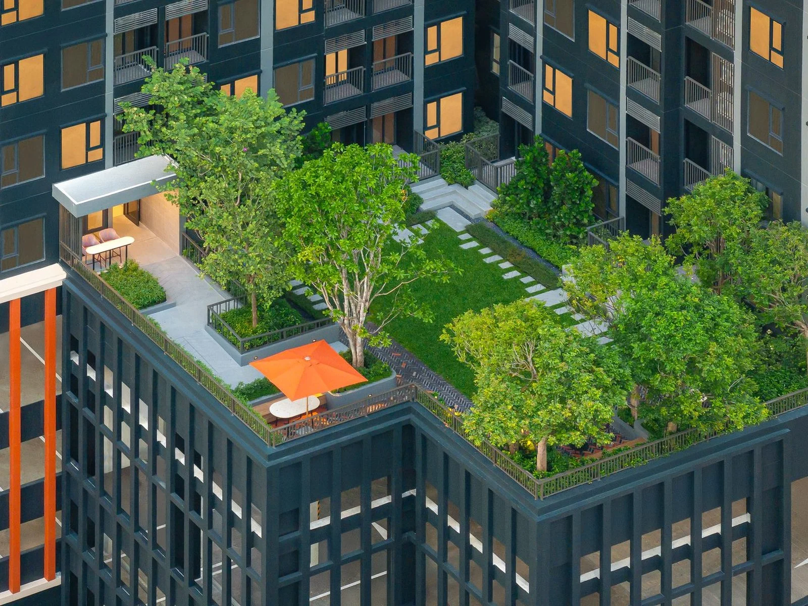 Landscaped rooftop garden with lawn, trees and orange-umbrella seating at FLO by Sansiri, Khlong San, Thailand
